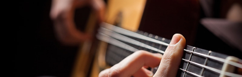 Focused shot of someone playing a chord on a guitar