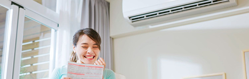 Happy woman with ductless hvac unit behind her