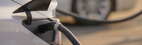 Close up of a charging car with an EV pump plugged in