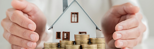 Small toy house with coins in front of it